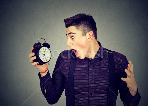 Stock photo: Anxious man looking at alarm clock. Time pressure concept 
