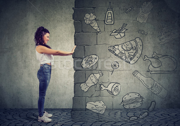 motivated young woman resisting temptation of eating fast foot and choosing better diet.  Stock photo © ichiosea