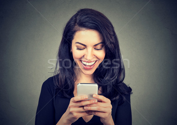 Stock photo: Laughing woman text messaging on smart phone having a pleasant chart conversation 