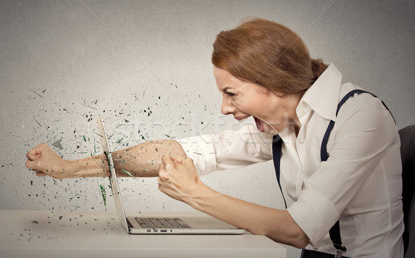 Furious businesswoman throws a punch into computer, screaming Stock photo © ichiosea