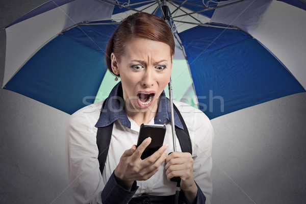 shocked woman reading breaking news on smartphone holding umbrella Stock photo © ichiosea