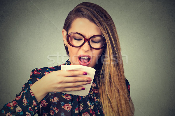young woman sneezing isolated on gray wall background. Studio shot.  Stock photo © ichiosea