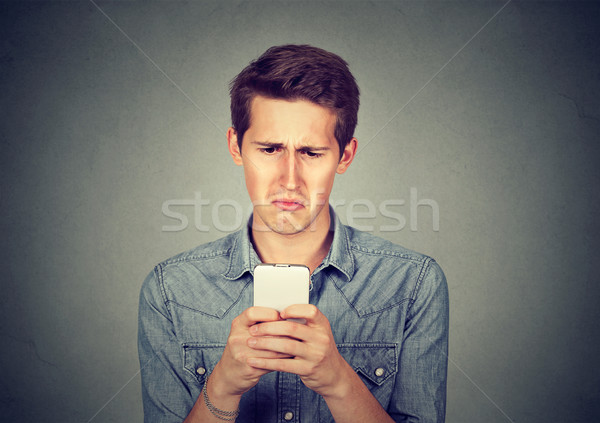 Upset stressed man holding cellphone disgusted with message received Stock photo © ichiosea
