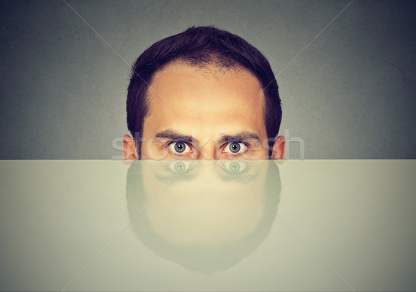 suspicious scared young man peeking from under the table hiding   
 Stock photo © ichiosea