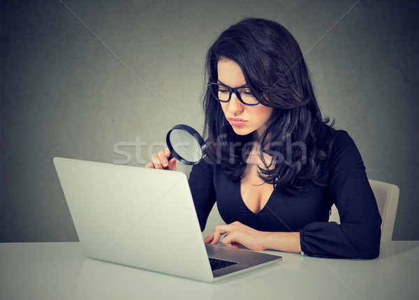 Woman looking at her laptop with magnifying glass Stock photo © ichiosea
