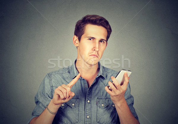 man with cell phone showing no, don't, attention with finger gesture Stock photo © ichiosea