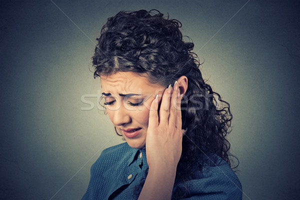 Tinnitus. Closeup sick female having ear pain touching painful head  Stock photo © ichiosea