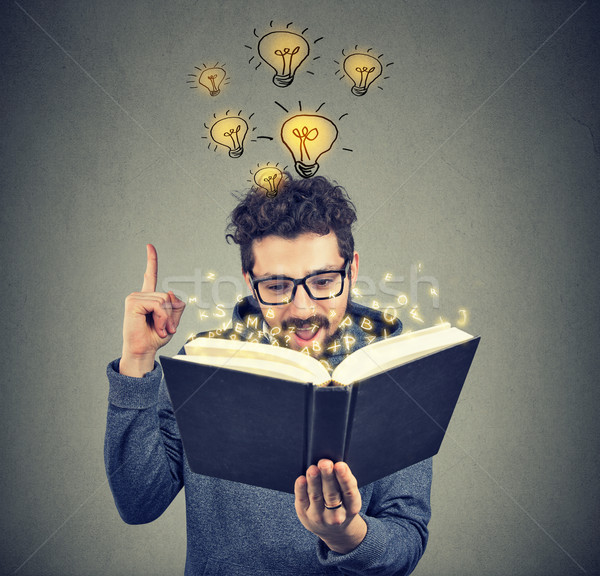 Stock photo: Smart man inspired with idea from book