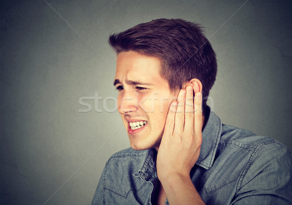 Tinnitus. Sick man having ear pain touching his painful head  Stock photo © ichiosea