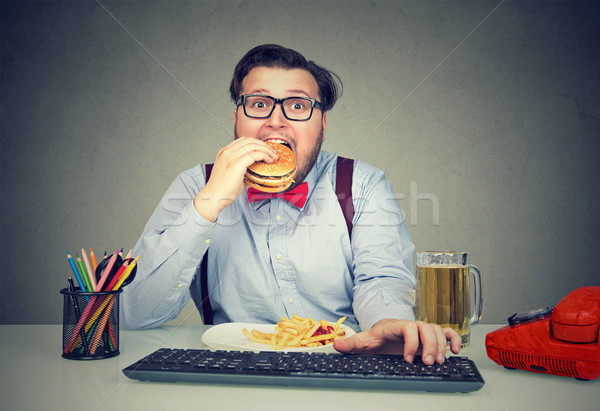 Hungry man eating fast food at work Stock photo © ichiosea