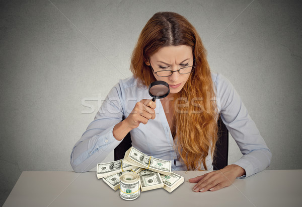 woman looking through magnifying glass on stack of dollar banknotes Stock photo © ichiosea