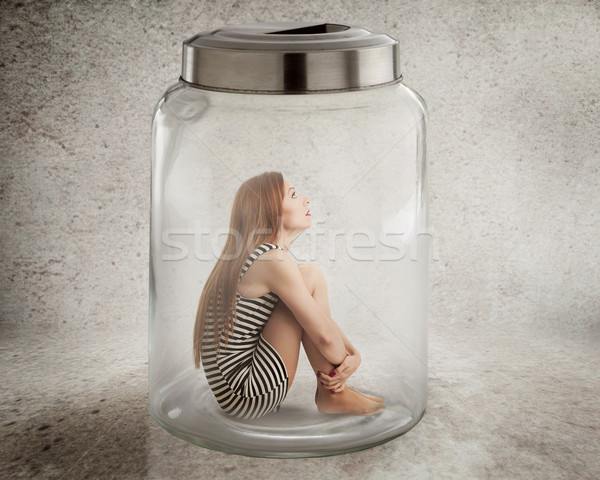 Stock photo: Young lonely woman sitting in glass jar 