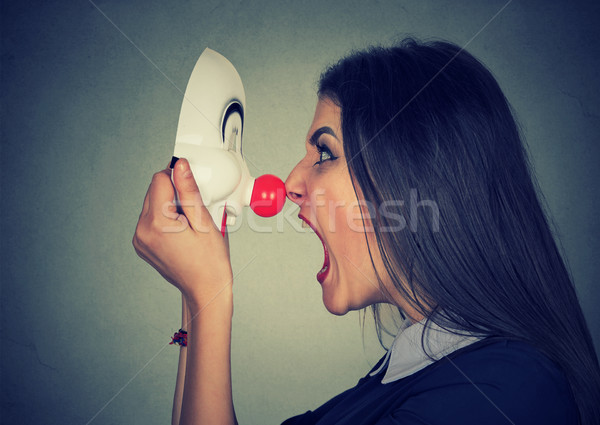 Stock photo: Angry woman screaming at happy clown mask 