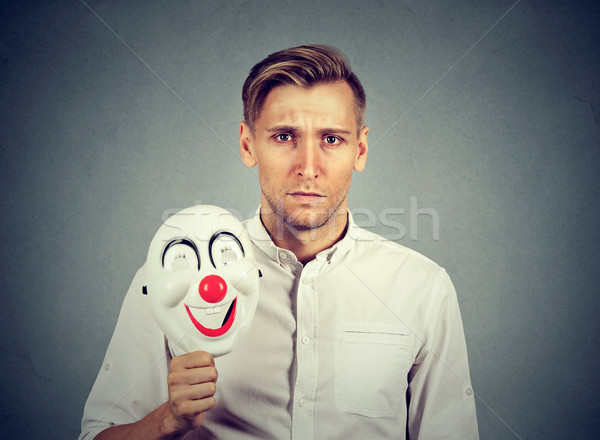 Young sad man with happy clown mask Stock photo © ichiosea