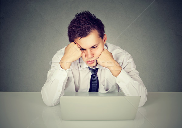 Stock photo: Overworked bored man sitting at desk with laptop computer looking down 