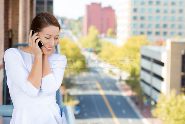 Beautiful woman talking on a cell phone, on a balcony of her city apartment Stock photo © ichiosea