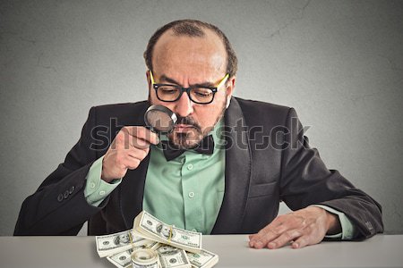 Business man looking through magnifying glass on stack of dollar banknotes Stock photo © ichiosea