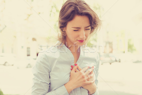 Stock photo: woman standing on a city street having heart pain 