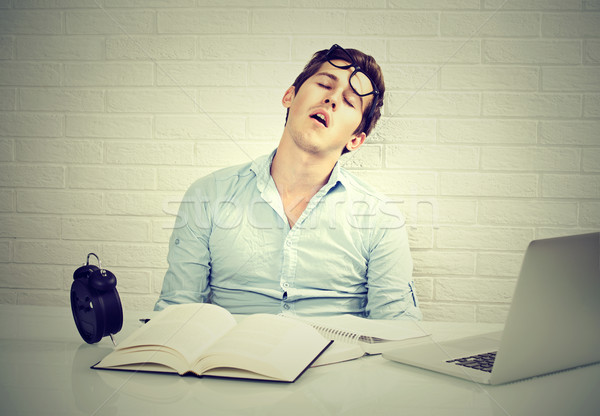 tired sleepy man sitting at desk with books in front of laptop Stock photo © ichiosea