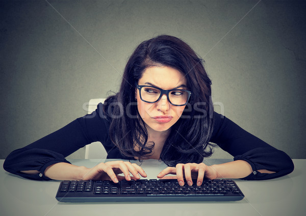 Crazy looking nerdy woman typing on the keyboard plotting a revenge  Stock photo © ichiosea