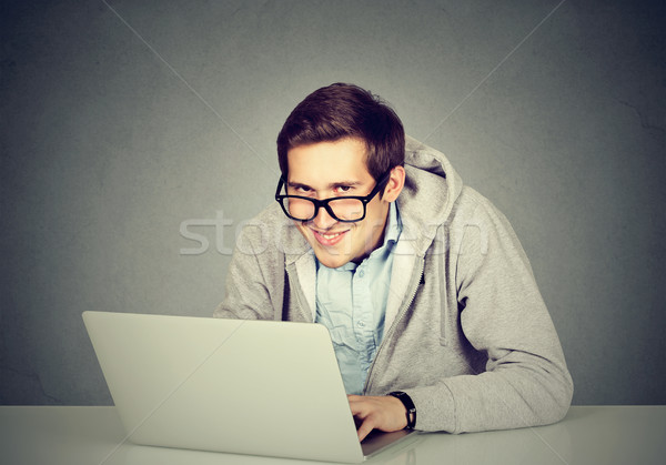 Young sly devious man using a laptop plotting server sabotage  Stock photo © ichiosea