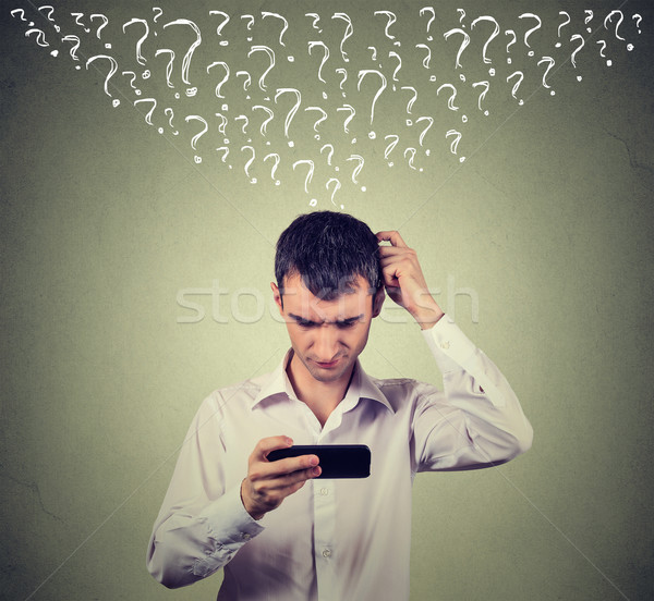 confused young man looking at his mobile smart phone has many questions Stock photo © ichiosea