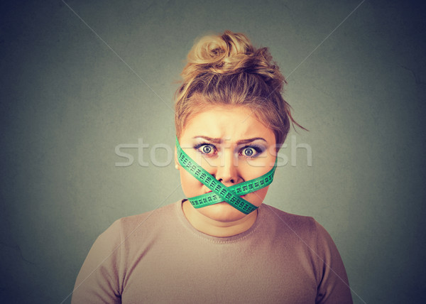 Stock photo: Diet restriction stress. Frustrated woman with measuring tape around her mouth 