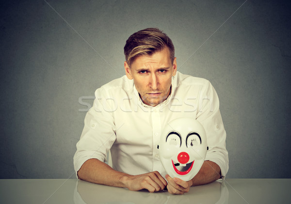 worried man with sad expression holding clown mask expressing cheerfulness Stock photo © ichiosea