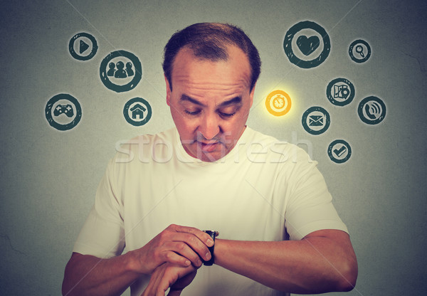 Middle age man using checking time on his smart watch with apps icons. New technology gadget concept Stock photo © ichiosea