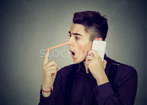 Stock photo: Surprised man with long nose talking on mobile phone Liar concept 