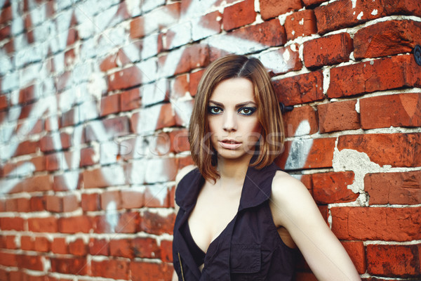 Caucasian blond woman standing behind brick wall Stock photo © igor_shmel