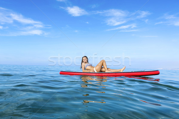 Stock photo: Woman relaxing over a paddle surfboard
