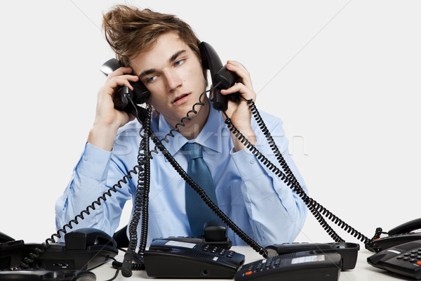 Jeune homme séance bureau plusieurs téléphones affaires Photo stock © iko