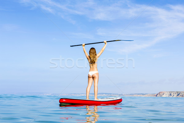 A beautiful and happy woman with arms up and learning paddle-sur Stock photo © iko