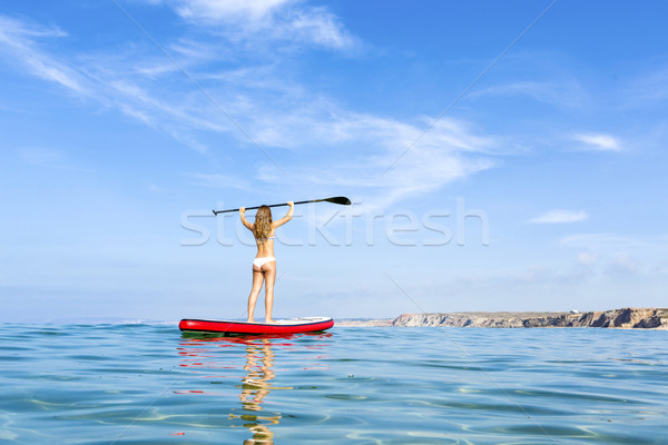 A beautiful and happy woman with arms up and learning paddle-sur Stock photo © iko