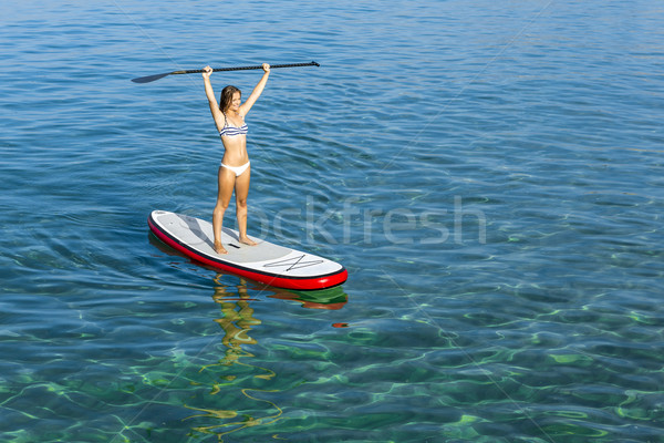 A beautiful and happy woman with arms up and learning paddle-sur Stock photo © iko