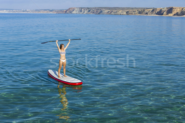 A beautiful and happy woman with arms up and learning paddle-sur Stock photo © iko