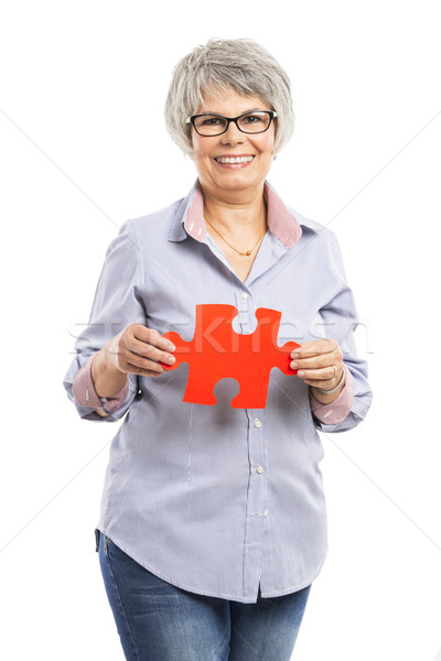 Elderly woman holding a puzzle piece Stock photo © iko