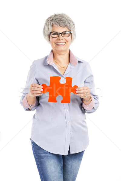 Elderly woman holding a puzzle piece Stock photo © iko