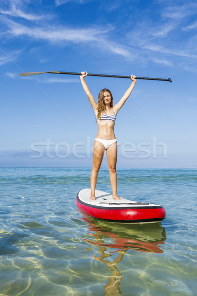 A beautiful and happy woman with arms up and learning paddle-sur Stock photo © iko