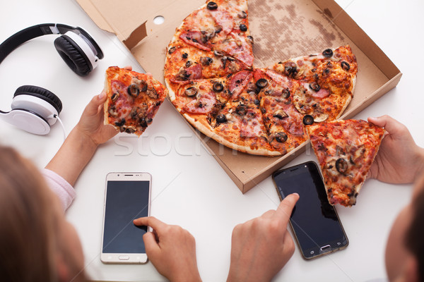 Young teenagers checking their phones while eating pizza - top v Stock photo © ilona75