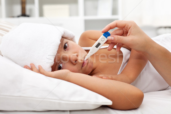 Sick child with fever laying in bed Stock photo © ilona75