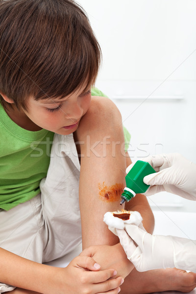 Boy receiving emergency treatment - disinfecting a wounded leg Stock photo © ilona75