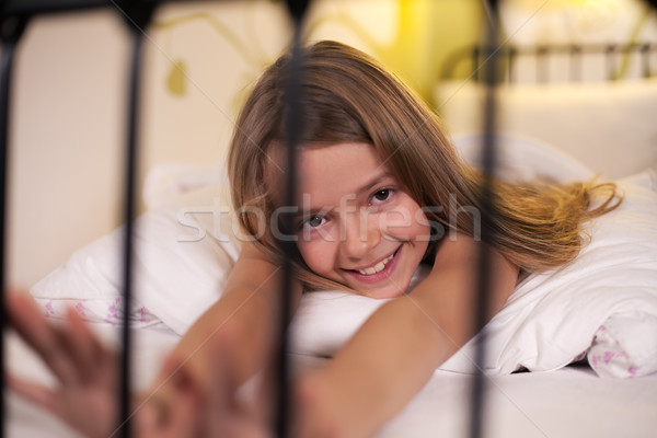 Young girl stretching in bed with a happy smile, shallow depth Stock photo © ilona75