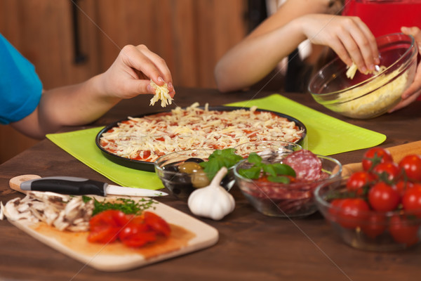 Kids making a pizza at home - putting the grated cheese on Stock photo © ilona75