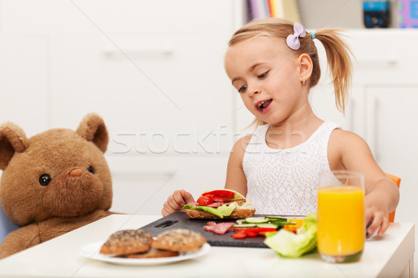 Little girl having a healthy snack sitting at the table with her Stock photo © ilona75