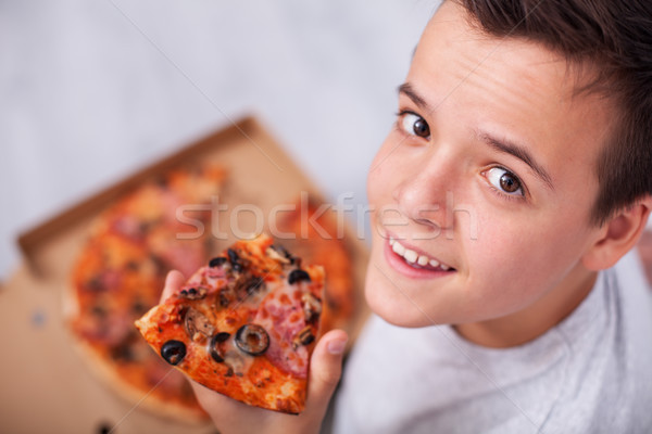 Happy young teenager boy eating a slice of pizza sitting on the  Stock photo © ilona75