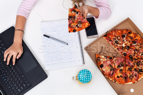 Young girl hands working at the desk while eating pizza - conven Stock photo © ilona75