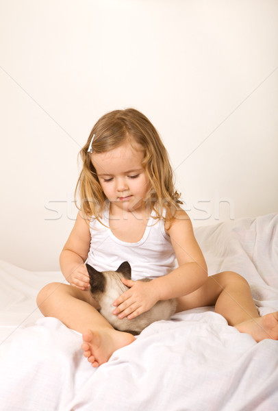 Little girl sitting in bed with her kitten Stock photo © ilona75