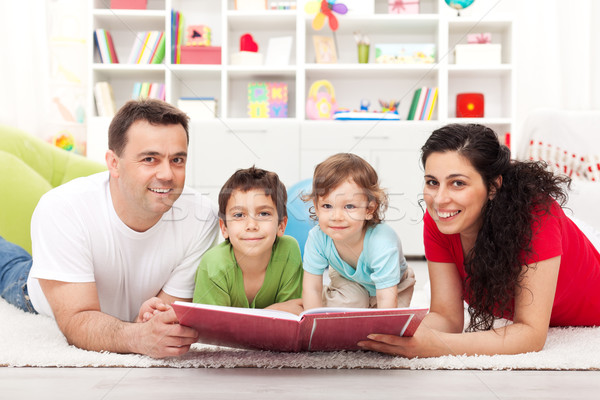 Young family with two kids reading a story book Stock photo © ilona75